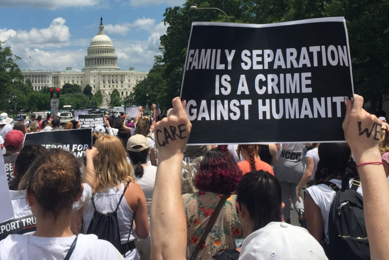 Marcher holds up a sign that reads "family separation is a crime against humanity" in front of the white house.