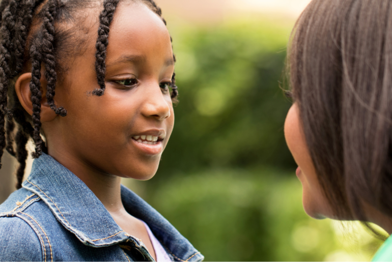 African american girl smiles as she speaks to an adult.