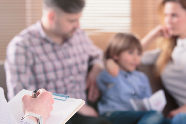 A therapist takes notes as a family talks among themselves.