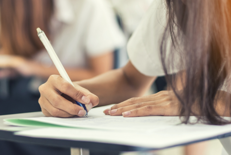 Student writing with her pencil on a test sheet.