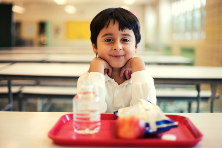 Boy sitting at school lunch table.