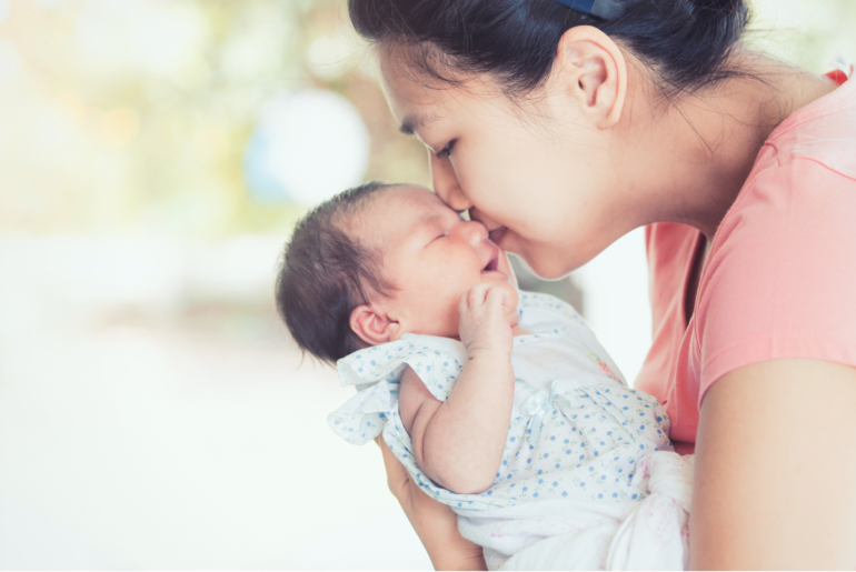 Mother kissing infant.
