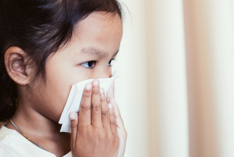 Sick girl blowing her nose.