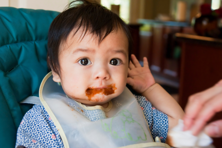 Messy baby eating solid food.
