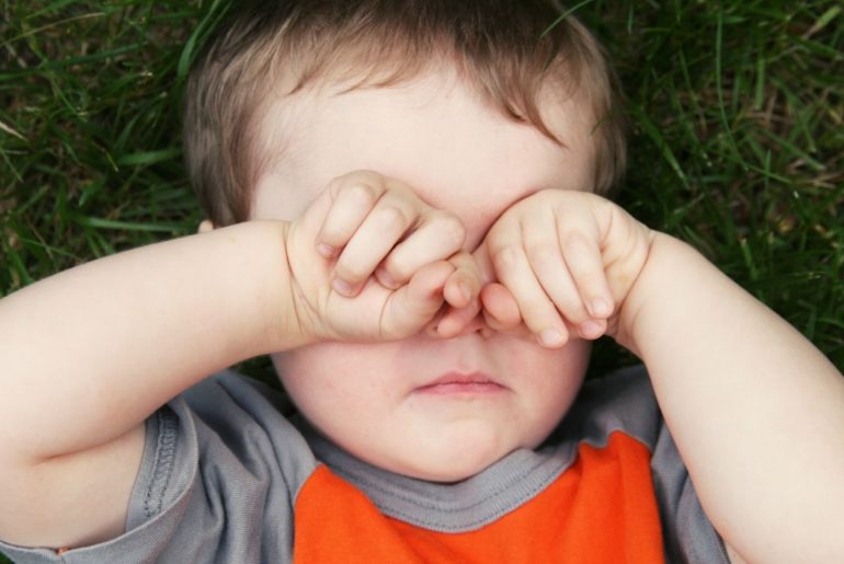 Sleepy boy rubbing his eyes.