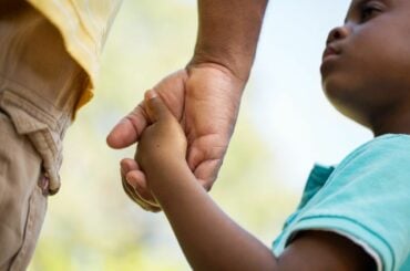Boy holding dad's hand.