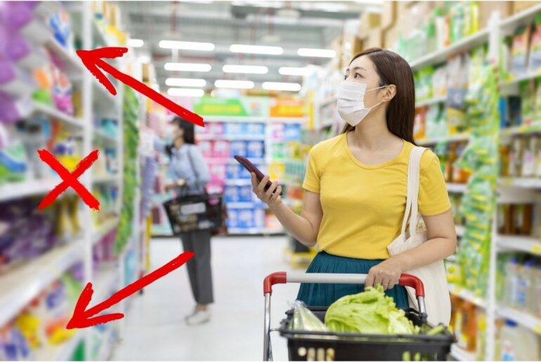 Masked woman looking at products in a grocery store aisle.