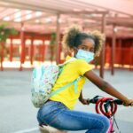 Girl wearing mask riding her bike to school.