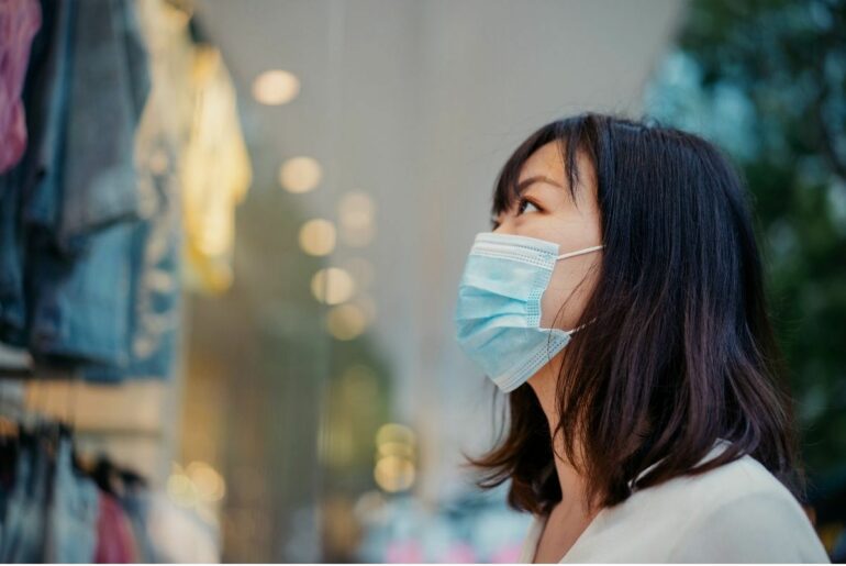 Woman window shopping with a face mask.