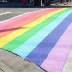 A newly painted crosswalk with rainbow stripes resembling a Pride flag