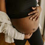 A pregnant belly sticks out from under a cropped shirt